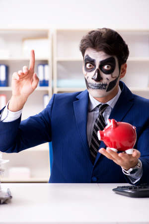 Businessmsn with scary face mask working in officeの写真素材