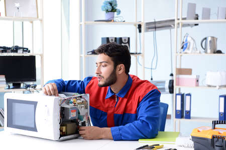 Young repairman fixing and repairing microwave ovenの写真素材