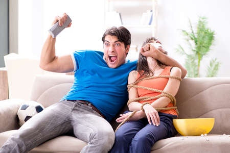 Man tying up his wife to watch sports football