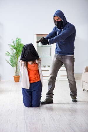 Armed man assaulting young woman at homeの写真素材