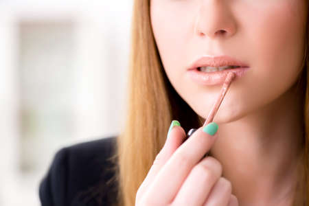 Woman applying lipstick with brushの写真素材