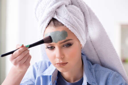 Woman applying clay mask with brush at home