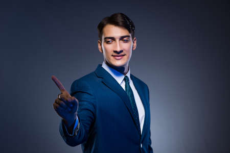 Businessman pressing virtual buttons on gray backgroundの写真素材