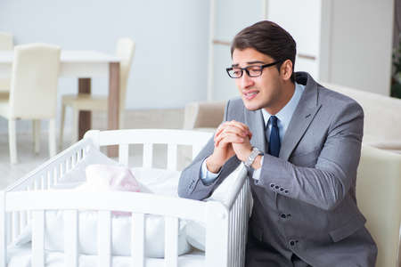 Young businessman trying to work from home caring after newborn babyの写真素材