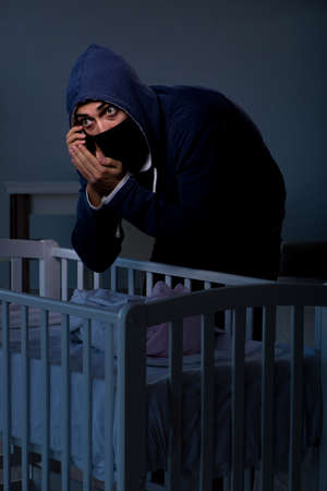 Criminal stealing baby in human child traficking conceptの写真素材