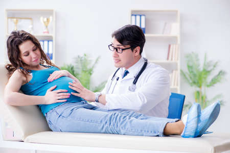 Doctor examining pregnant female patient in hospitalの写真素材