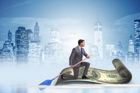 Businessman rowing on dollar boat in business financial conceptの写真素材