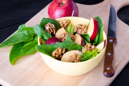 Spinach salad with nuts and apples served on tableの写真素材