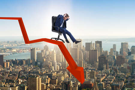 Businessman sliding down on chair in economic crisis conceptの写真素材