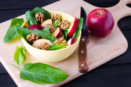 Spinach salad with nuts and apples served on tableの写真素材