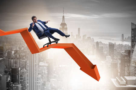 Businessman sliding down on chair in economic crisis conceptの写真素材