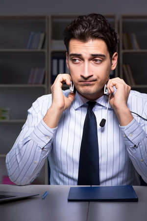 Tired and exhausted helpdesk operator during night shiftの写真素材