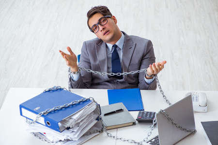Busy employee chained to his office deskの写真素材