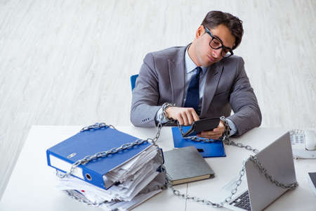 Busy employee chained to his office deskの写真素材