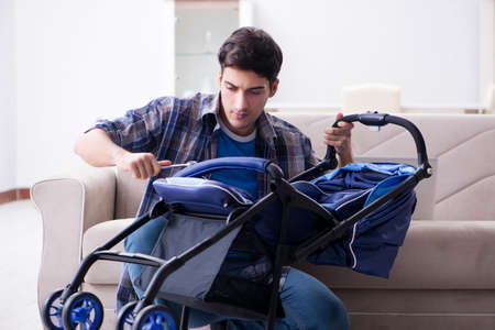 Young father assembling baby pram at homeの写真素材