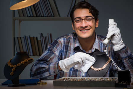 Young male jeweller working at night in his workshopの写真素材