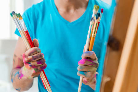 Young funny artist working on new painting in his studioの写真素材