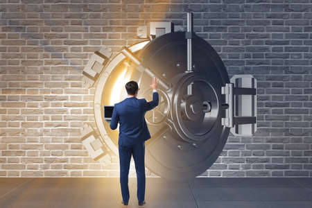 Businessman in front of banking vault doorの写真素材