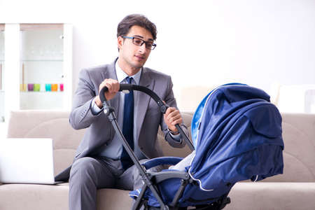 Businessman looking after newborn baby at home and teleworkingの写真素材