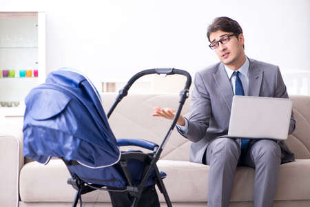 Businessman looking after newborn baby at home and teleworking