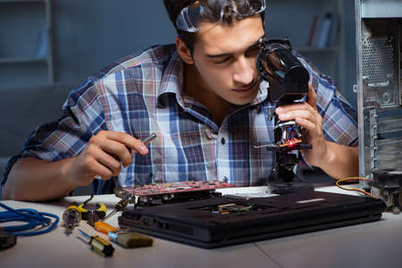 Repairman trying to repair laptop with miscroscopeの写真素材