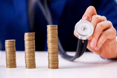 Businessman with stacks of coins in the officeの写真素材