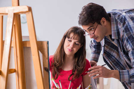 Artist coaching student in painting class in studioの写真素材