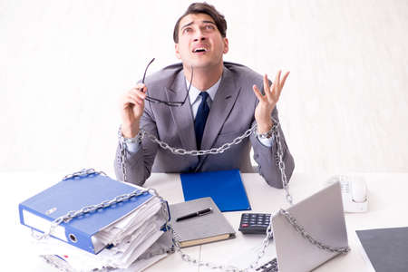 Busy employee chained to his office deskの写真素材