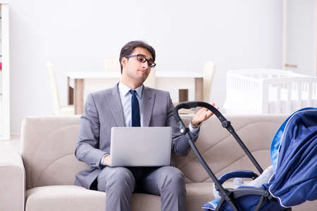 Businessman looking after newborn baby at home and teleworking