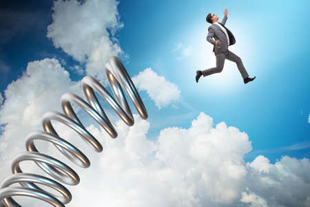 Businessman jumping from spring in promotion conceptの写真素材