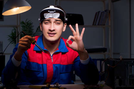 Computer specialist repairing PC late at night