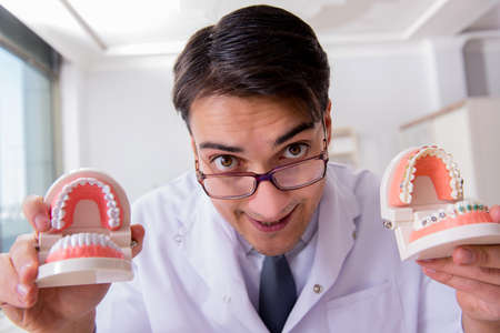 Funny dentist with teeth model in hospital