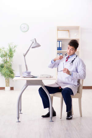 Young handsome doctor working in hospital roomの写真素材