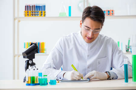 Young chemist student working in lab on chemicalsの写真素材