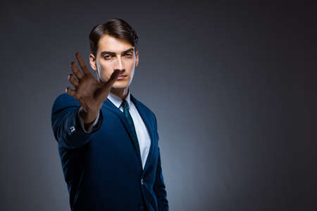 Businessman pressing virtual buttons on gray backgroundの写真素材