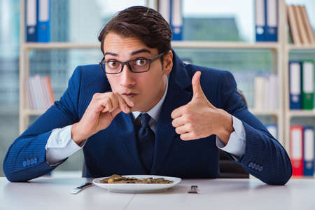 Funny businessman eating gold coins in officeの写真素材