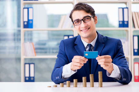Businessman with stacks of coins in the officeの写真素材