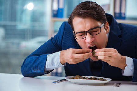 Funny businessman eating gold coins in officeの写真素材