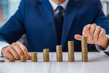 Businessman with stacks of coins in the officeの写真素材