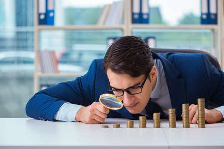Businessman with stacks of coins in the officeの写真素材