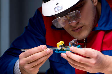 Computer specialist repairing PC late at nightの写真素材