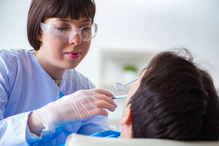 Woman dentist doctor with male patient in hospitalの写真素材