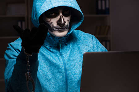 Scary hacker hacking security firewall late in officeの写真素材