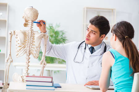 Doctor showing type of injury on skeleton to patientの写真素材