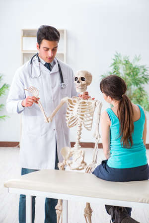 Doctor showing type of injury on skeleton to patientの写真素材