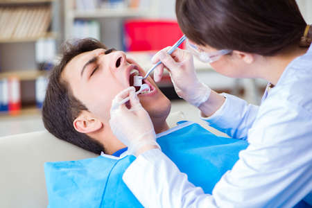 Woman dentist doctor with male patient in hospitalの写真素材