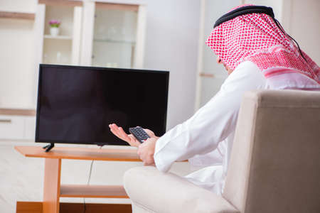 Arab businessman watching tv at homeの写真素材