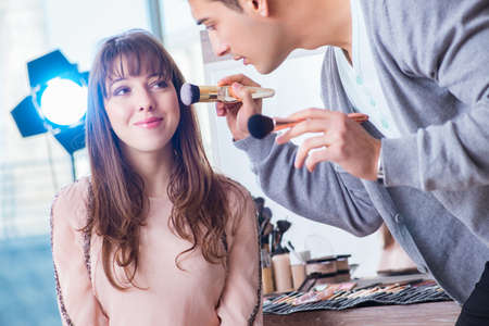 Man doing make-up for cute woman in beauty salon