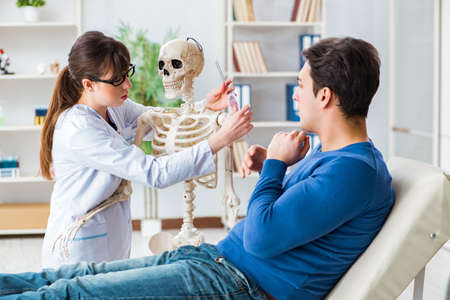 Doctor showing type of injury on skeleton to patientの写真素材