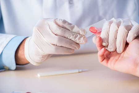 Doctor taking blood samples from finger